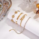 Close-up of four GIVCHO 18K gold plated bangle bracelets with colorless cubic zirconia stones, stacked on a wrist.