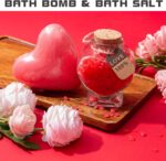 Red heart-shaped gift box open to reveal a 12 oz insulated tumbler, bath bomb, mirror, soap roses, and other spa items.