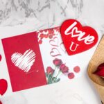 Red heart-shaped gift box open to reveal a 12 oz insulated tumbler, bath bomb, mirror, soap roses, and other spa items.
