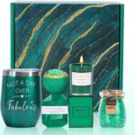 An emerald green spa gift basket featuring a bath bomb, body salt, candle, gem soap, and a stainless steel wine mug.