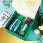 An emerald green spa gift basket featuring a bath bomb, body salt, candle, gem soap, and a stainless steel wine mug.